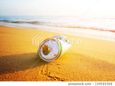 Crumpled beer can on sand beach at sea. Discarded broken can at seashore. Environmental pollution Crumpled beer can on sand beach at sea. Discarded broken can at seashore. Environmental pollution 139583308