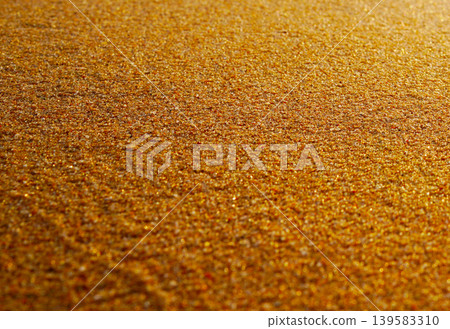 Sand background. Warm golden sand covers ground at beach during sunset with sun rays reflecting Sand background. Warm golden sand covers ground at beach during sunset with sun rays reflecting 139583310