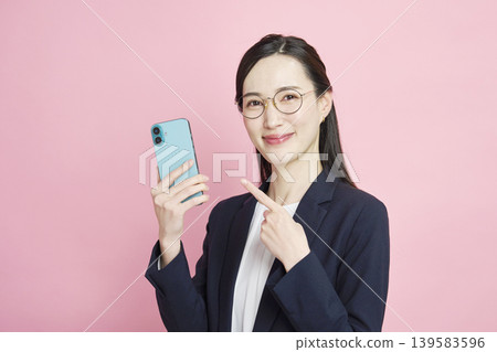 Smiling business woman pointing at smartphone Smiling business woman pointing at smartphone 139583596