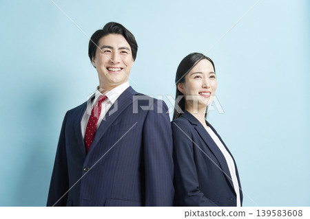 一群男女商務人士並肩站著，面帶微笑，背景是淺藍色。 139583608