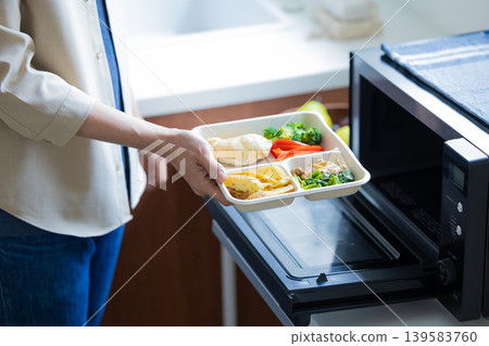 A man's hands as he microwaves a frozen bento box. A man's hands as he microwaves a frozen bento box. 139583760