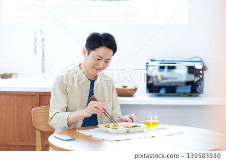一名男子正在吃微波爐加熱的外帶食品。 一名男子正在吃微波爐加熱的外帶食品。 139583930