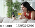 Satisfied asian woman paying online using credit card and cell phone 139584290