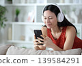 Serious asian woman wearing headphone watching media 139584291