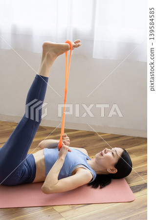 一位身穿瑜珈服的中年日本女性正在使用阻力帶進行鍛鍊。 139584585