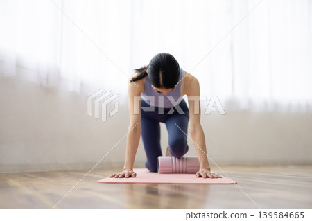 一位身穿瑜珈服的中年日本女性正在使用泡沫軸進行自我按摩。 139584665