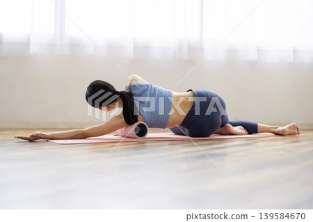一位身穿瑜珈服的中年日本女性正在使用泡沫軸進行自我按摩。 139584670