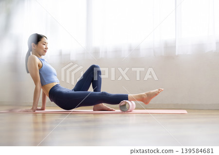 一位身穿瑜珈服的中年日本女性正在使用泡沫軸進行自我按摩。 139584681
