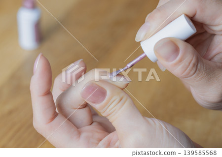 A woman is wearing gel nail polish on the middle finger of her left hand. A woman is wearing gel nail polish on the middle finger of her left hand. 139585568