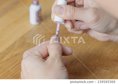 A woman is wearing gel nail polish on the middle finger of her left hand. A woman is wearing gel nail polish on the middle finger of her left hand. 139585569