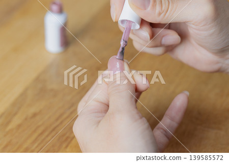 A woman is wearing gel nail polish on her left thumb. A woman is wearing gel nail polish on her left thumb. 139585572