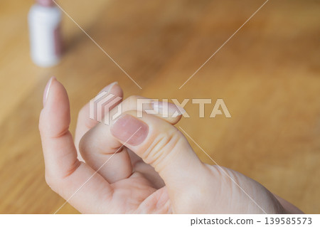 A woman is wearing gel nail polish on the middle finger of her left hand. A woman is wearing gel nail polish on the middle finger of her left hand. 139585573
