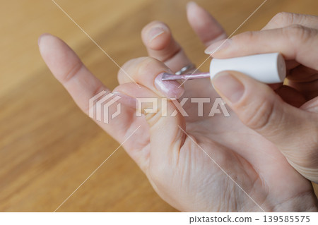 A woman is wearing gel nail polish on the middle finger of her left hand. A woman is wearing gel nail polish on the middle finger of her left hand. 139585575