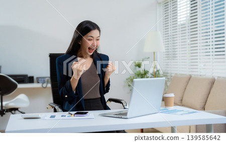 Overjoyed charming excited asian business woman worker using laptop and tablet working in office, feeling happy. Overjoyed charming excited asian business woman worker using laptop and tablet working in office, feeling happy. 139585642