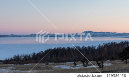 Winter sunset over Lake Baikal ice and distant mountains in Maloye More strait 139586458