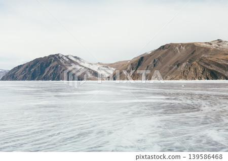 Frozen Lake Baikal winter landscape with mountain shoreline and clear ice Frozen Lake Baikal winter landscape with mountain shoreline and clear ice 139586468