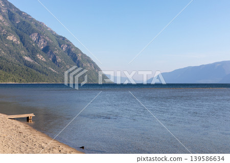 Scenic shoreline of Lake Teletskoye with Altai Mountains under clear blue sky Scenic shoreline of Lake Teletskoye with Altai Mountains under clear blue sky 139586634
