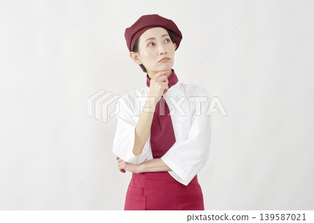 一位女咖啡店員在白色背景前沉思。 139587021