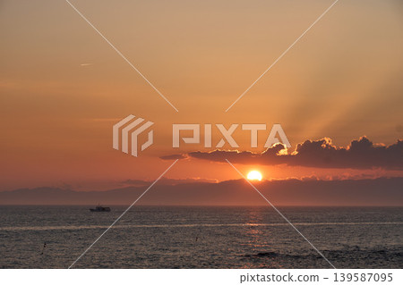 [Minamichita] An orange sunset sinking between clouds over the sea 139587095