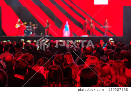 Crowd watching live concert on stage with band and dramatic red lighting 139587368
