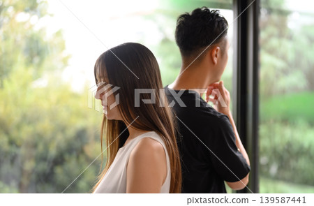 Profiles of a man and a woman standing by a window 139587441