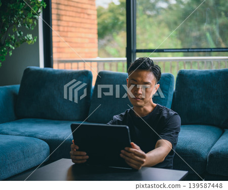 A man seeing a tablet in the living room 139587448