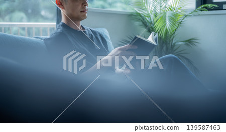A man is reading on the sofa. A man is reading on the sofa. 139587463