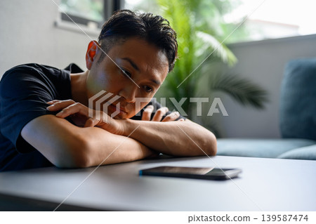 A man staring at his smartphone at his desk. A man staring at his smartphone at his desk. 139587474
