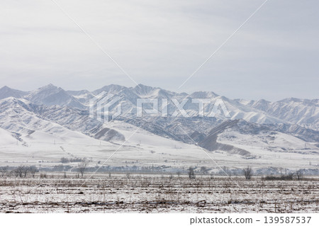 Snowy Tian Shan mountain range landscape in Kyrgyzstan with winter valley view Snowy Tian Shan mountain range landscape in Kyrgyzstan with winter valley view 139587537