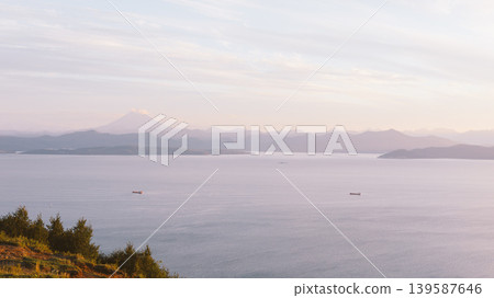 Avacha Bay seascape with ships and distant volcano at soft sunrise light Avacha Bay seascape with ships and distant volcano at soft sunrise light 139587646