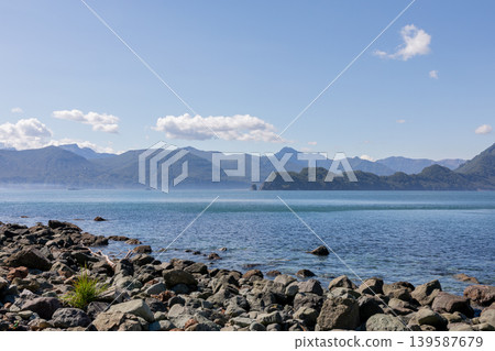 Rocky shoreline and calm sea in Velyuchinskaya Bay with mountain panorama Rocky shoreline and calm sea in Velyuchinskaya Bay with mountain panorama 139587679