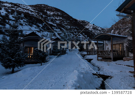 Snowy cottages and mountain slope at Chunkurchak Valley winter resort at dusk Snowy cottages and mountain slope at Chunkurchak Valley winter resort at dusk 139587728