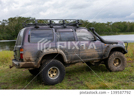 Muddy off-road SUV parked by lake near Vachkazhets mountain range, Kamchatka Muddy off-road SUV parked by lake near Vachkazhets mountain range, Kamchatka 139587792
