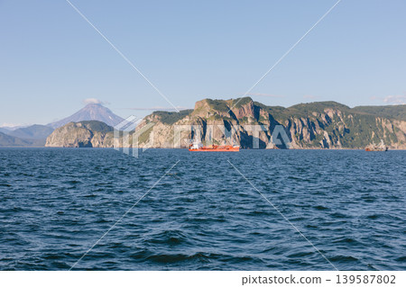 Avacha Bay seascape with cargo ship and volcanic mountains, Kamchatka coast Avacha Bay seascape with cargo ship and volcanic mountains, Kamchatka coast 139587802