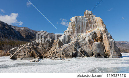 Rocky cliff on frozen Lake Baikal shoreline under blue sky in winter Siberia 139587858