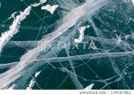 Aerial view of cracked turquoise ice on Lake Baikal in winter, natural texture Aerial view of cracked turquoise ice on Lake Baikal in winter, natural texture 139587862