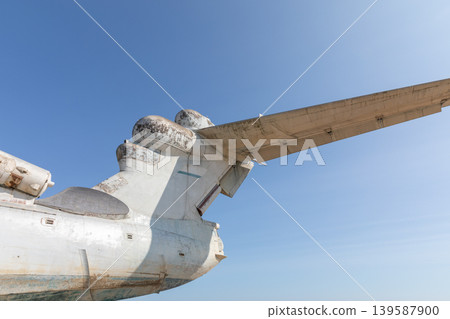 Close-up of abandoned ekranoplan wing and tail against clear blue sky Close-up of abandoned ekranoplan wing and tail against clear blue sky 139587900
