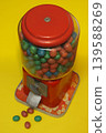 A vintage candy dispenser filled with colorful candies on yellow background 139588269