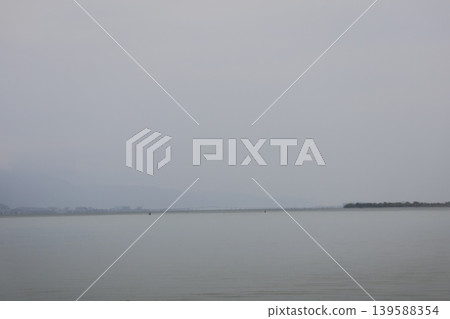 Lake Biwa and the hazy landscape of land, mountains, and sky on the opposite shore. Lake Biwa and the hazy landscape of land, mountains, and sky on the opposite shore. 139588354