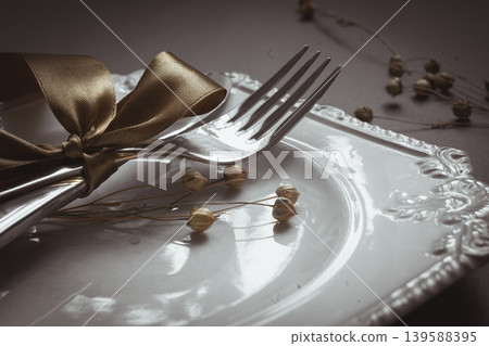 Romantic tabble setting with ribbon, plates, cutlery on black background. Empty plate. Mockup design layout for your text. Love romantic concept. Copy space. Top view. Flat lay. Romantic tabble setting with ribbon, plates, cutlery on black background. Empty plate. Mockup design layout for your text. Love romantic concept. Copy space. Top view. Flat lay. 139588395