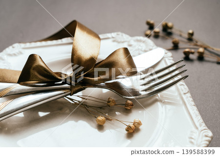 Romantic tabble setting with ribbon, plates, cutlery on black background. Empty plate. Mockup design layout for your text. Love romantic concept. Copy space. Top view. Flat lay. Romantic tabble setting with ribbon, plates, cutlery on black background. Empty plate. Mockup design layout for your text. Love romantic concept. Copy space. Top view. Flat lay. 139588399
