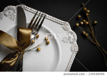 Romantic tabble setting with ribbon, plates, cutlery on black background. Empty plate. Mockup design layout for your text. Love romantic concept. Copy space. Top view. Flat lay. 139588494
