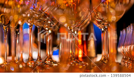 Elegant scene of wine being poured into glasses aligned in a row, showcasing the rich colors and graceful flow of the liquid, set against a dark, warm background, ideal sophisticated dining settings Elegant scene of wine being poured into glasses aligned in a row, showcasing the rich colors and graceful flow of the liquid, set against a dark, warm background, ideal sophisticated dining settings 139588504