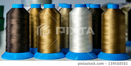 Multicolored spools thread. Spools of multi-colored threads lies on white table, close-up shot photo Multicolored spools thread. Spools of multi-colored threads lies on white table, close-up shot photo 139588581