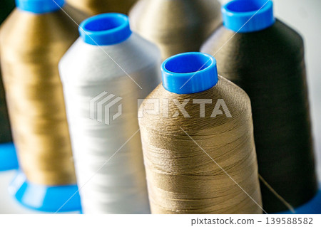 Multicolored spools thread. Spools of multi-colored threads lies on white table, close-up shot photo Multicolored spools thread. Spools of multi-colored threads lies on white table, close-up shot photo 139588582