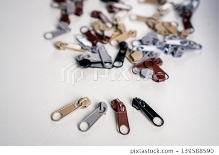 Metal zipper slide isolated on white. Assortment of zipper slides. Clothing element. Metal zipper slide isolated on white. Assortment of zipper slides. Clothing element. 139588590