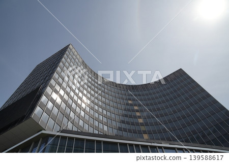 Modern curved building with curved facade and horizontal stripe design against the sky. Modern curved building with curved facade and horizontal stripe design against the sky. 139588617