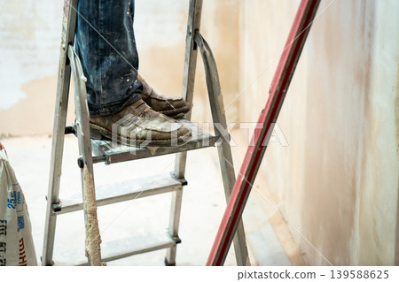 Happy worker man making wall in the room by hand spatula repair Happy worker man making wall in the room by hand spatula repair 139588625