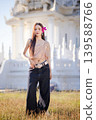 Trendy Thai fashion woman wearing a traditional Sabai paired with denim jeans at temple, reflecting the growing fashion trend in Thailand that blends cultural heritage with contemporary street style. 139588766