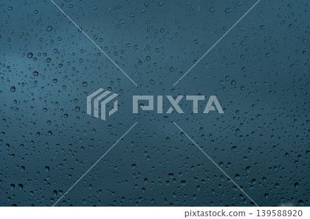 A rainy day window view. Rain drops on window. Condensed rain drop on the car glass window on a rainy day. Dew moisture condensation on wet mirror background. Fresh weather. Water raindrop bg A rainy day window view. Rain drops on window. Condensed rain drop on the car glass window on a rainy day. Dew moisture condensation on wet mirror background. Fresh weather. Water raindrop bg 139588920